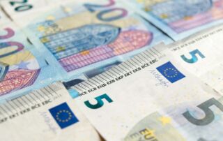 Slika prikazuje evro bankovce v vrednosti pet in dvajset evrov položenih drug poled drugega.