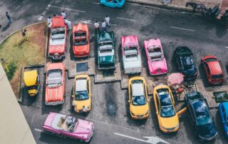 Slika prikazuje parkirišče z roza in rumenimi taksi avtomobili v New York stilu.