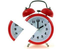 Slika prikazuje budilko rdeče barve v vintage stilu. Del budilke je odrezan.