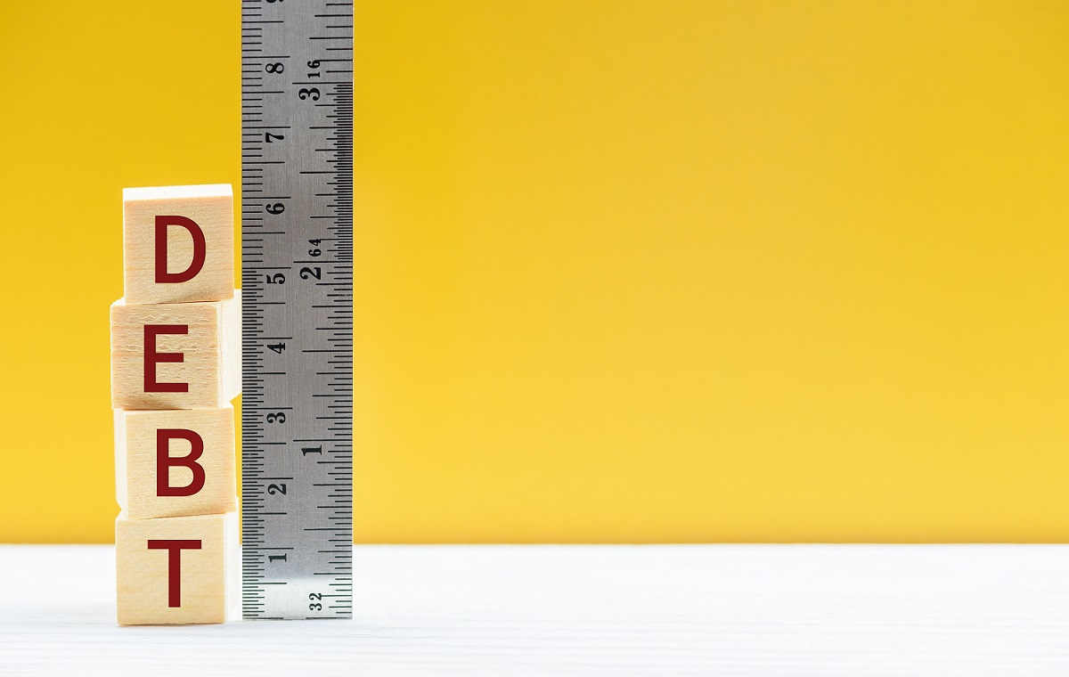 Merjenje velikosti finančnega dolga, kocke postavljene druga na drugo in ravnilo, prikazujejo stopnjo dolga, ki ga dolžnik dolguje svojemu upniku.