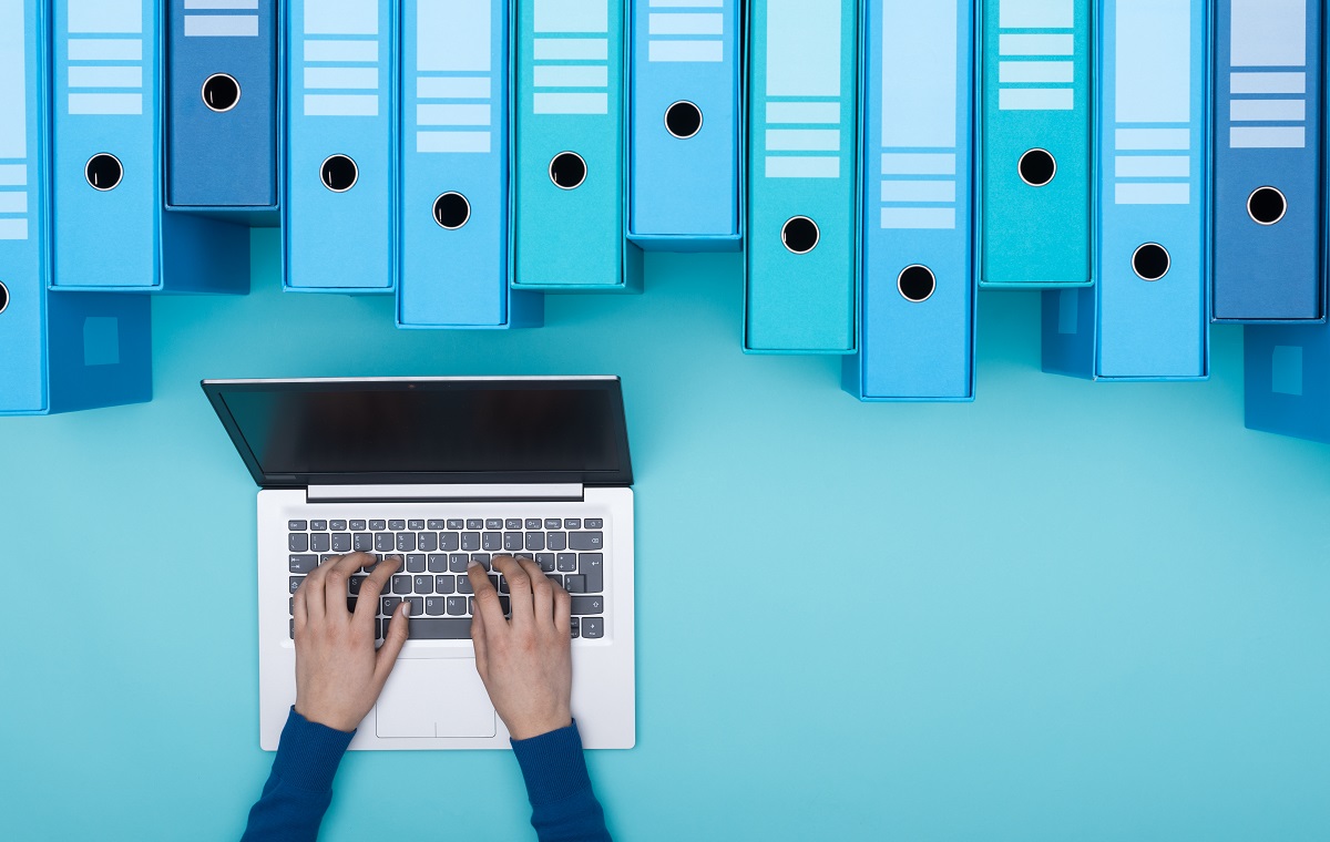 Ženska v arhivu išče pomembne datoteke v številnih mapah, kar ponazarja učinkovit sistem shranjevanja dokumentov.